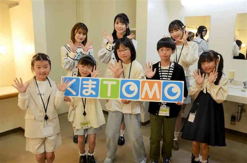 HKT48の田中伊桜莉さん（後列左）と森﨑冴彩さん（後列中央）と一緒に、アイドルさながらのポーズで写真に納まるくまTOMOサポーターの6人＝3月23日、益城町