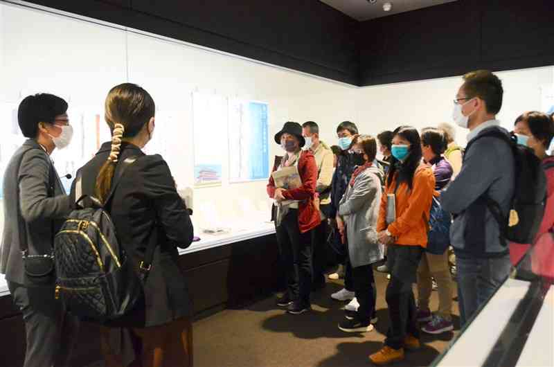 学芸員（左端）の説明を聞く台湾人の参加者ら＝24日、熊本市中央区